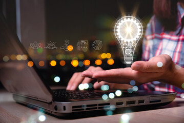 Fototapete - hand of a woman with a light bulb And there is a gear icon in it And he is using a notebook computer. The idea of ​​inspiration from online technology. innovation idea concept