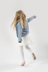 Wall Mural - Studio portrait of beautiful cheerful fashionable little girl wearing tutu skirt and denim jacket on white background