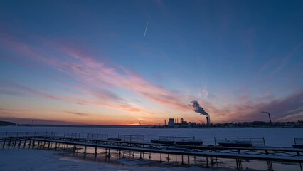 Wall Mural - Time-lapse sunrise over beautiful lake. Water surface in fast motion. Warm sky with rolling clouds. Trees silhouette woodland on horizon. Early morning shot in timelapse. Bright sun rises over skyline