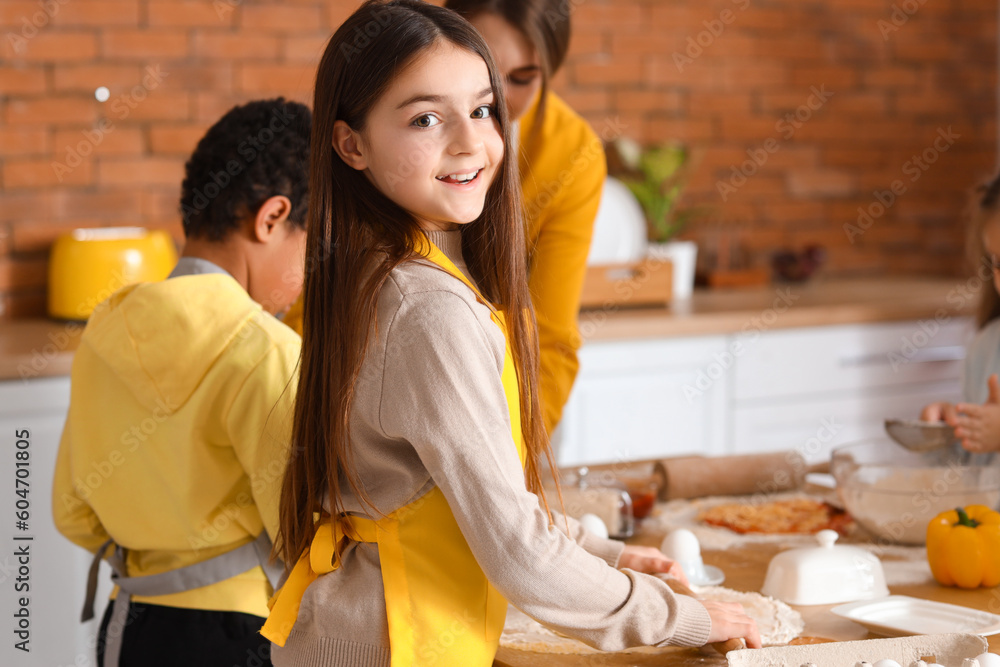 Little girl preparing pizza during cooking class in kitchen