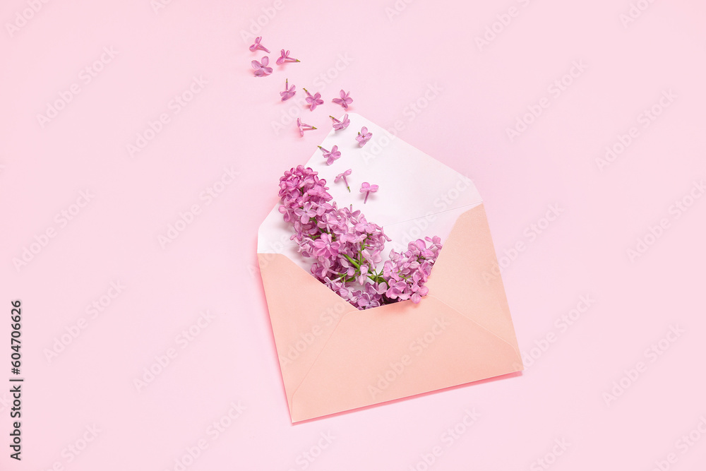 Envelope with beautiful blooming lilac flowers on pink background
