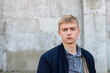 © Georgi - Serious looking Young blond man in casual clothes looking at the camera outdoors on the street.