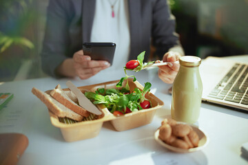 Modern woman employee in green office eating salad