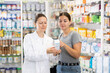 Pharmacist advises customer in a pharmacy, offers medicine for body care