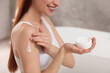 © New Africa - Young woman applying body cream onto shoulder in bathroom, closeup