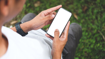 over shoulder view of young man holding smart phone with blank screen..