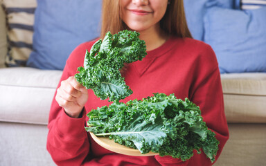 Wall Mural - Closeup image of a young woman holding and picking up kale leaves