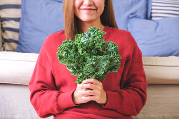 Wall Mural - Closeup image of a young woman holding kale leaves