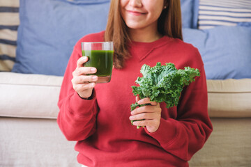 Wall Mural - Closeup image of a young woman holding kale leaves and kale smoothie