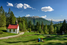 Austria, Tyrol, Hiking Pair Resting In Front Of Alpine Chapel