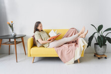 Woman Reading Book On Yellow Sofa In Living Room