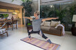© Westend61 - Woman practicing Warrior 2 pose on exercise mat in living room at home