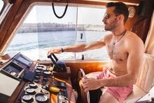 Shirtless Young Man Driving Yacht At Vacation