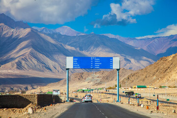 Road to Lamayuru,Ladakh city in India.Urban landscape with mountain background.Tourist in car with traffic sign.Blue sky with cloud.Landscape of Asia.