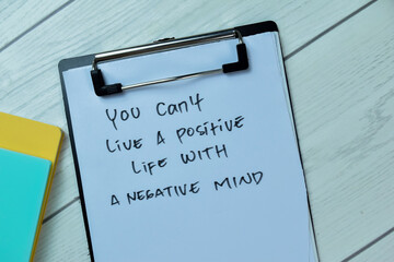 Concept of You Can't Live a Positive Life With A Negative Mind write on paperwork isolated on Wooden Table.