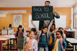 © Jacob Lund - Teacher and students holding up a back to school sign in a classroom