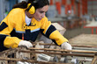 © Nassorn - Female industrial engineer in white helmet, safety jacket and headphone work in heavy metal engineering factory. Latin technician woman inspecting production line in metalwork warehouse facility.