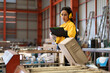 © Nassorn - Female industrial engineer in white helmet, safety jacket and headphone work in heavy metal engineering factory. Latin technician woman worker using clipboard in metalwork manufacturing facility.