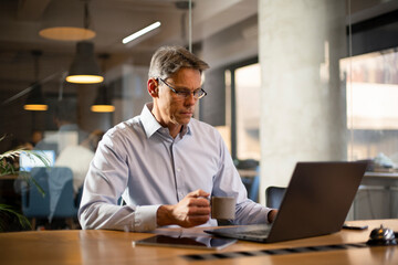 Businessman working with laptop at office. Businessman sitting at office desk working on laptop computer..
