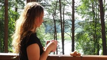 Happy Woman Relaxing And Looking Forest And Lake At Countryside Home Or Homestay In The Morning. Drinks Tea Or Coffee. Taking Photos And Selfies. Vacation, Blogger, SoloTravel, Journey, Trip