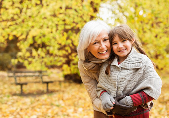 Wall Mural - Older woman and granddaughter smiling in park