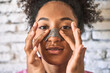 Confident young woman, fresh from shower, applies pore patch on nose for personal skincare.