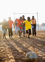 Wall Mural - Boys playing soccer together in dirt field