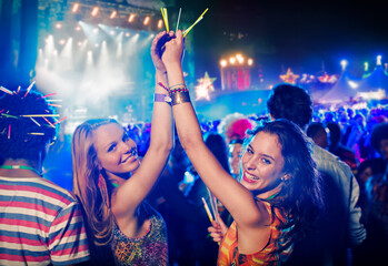 Wall Mural - Portrait of cheering women with glow sticks at music festival