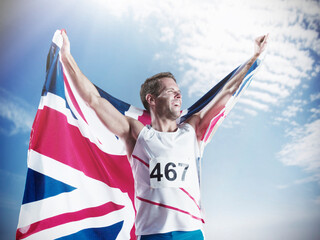 Wall Mural - Track and field athlete holding British flag and celebrating