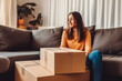 © VisualProduction - Woman holding cardboard box package sitting on sofa at home. Online shopping home delivery. Generative AI