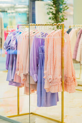 Wall Mural - Womens summer clothes hanging on rail. Blurred View through shop window