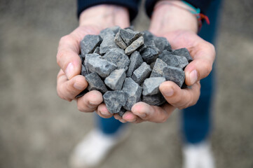 Gravel in the hands of a quarry worker. Worker holding pebbles in hands. Crushed stone quarry in the hands of a man.