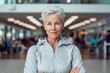 © Markus Schröder - Medium shot portrait photography of a glad mature woman wearing a comfortable tracksuit against a modern fitness center background. With generative AI technology