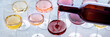 Red wine pour into a glass at a tasting panorama. Rose, red, and white wine, drinks on a table. An assortment of wines of many different colors