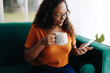 Mature woman having coffee and reading news updates on her phone