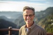 Lifestyle portrait photography of a grinning mature man wearing an elegant long-sleeve shirt against a scenic mountain overlook background. With generative AI technology
