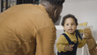 © Synthex - African American baby walking unsteadily, smiling father watching baby's steps