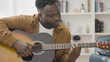 © Synthex - African American man learning to play guitar, musician rehearsing new single