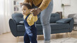 © Synthex - Loving father helps his little baby stand up and walk across the room, happy parenthood