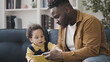 © Synthex - African American dad showing a book to toddler, father on parental leave