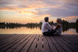 © luengo_ua - Romantic holiday. Senior loving couple sitting together on lake bank enjoying beautiful sunset.