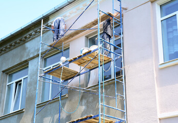 Sticker - Builder contractors  painting walls outside house facade. Close up on painting house outside wall during house renovation.