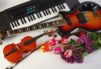 Wall Mural - Musical instruments electric guitar, violin and synthesizer, a bouquet of tulips on a light background.