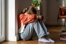 Depression In Teens. Upset Teenage Girl Sitting Alone On Floor And Crying, Feeling Sad And Depressed. Lonely Teenager Child Having Thoughts Of Suicide. Mental Health Of Adolescents