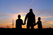© kittyfly - black silhouettes of men, children on the background of a colored sunset sky, field in the evening, the concept of beauty of nature, healthy lifestyle, active people, happy family