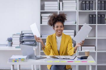 Wall Mural - Young business african american woman office worker analyst sitting at desk working on laptop thinking on project plan, analyzing marketing or financial data online, watching elearning webinar.