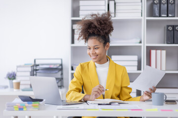 Wall Mural - Young business african american woman office worker analyst sitting at desk working on laptop thinking on project plan, analyzing marketing or financial data online, watching elearning webinar.