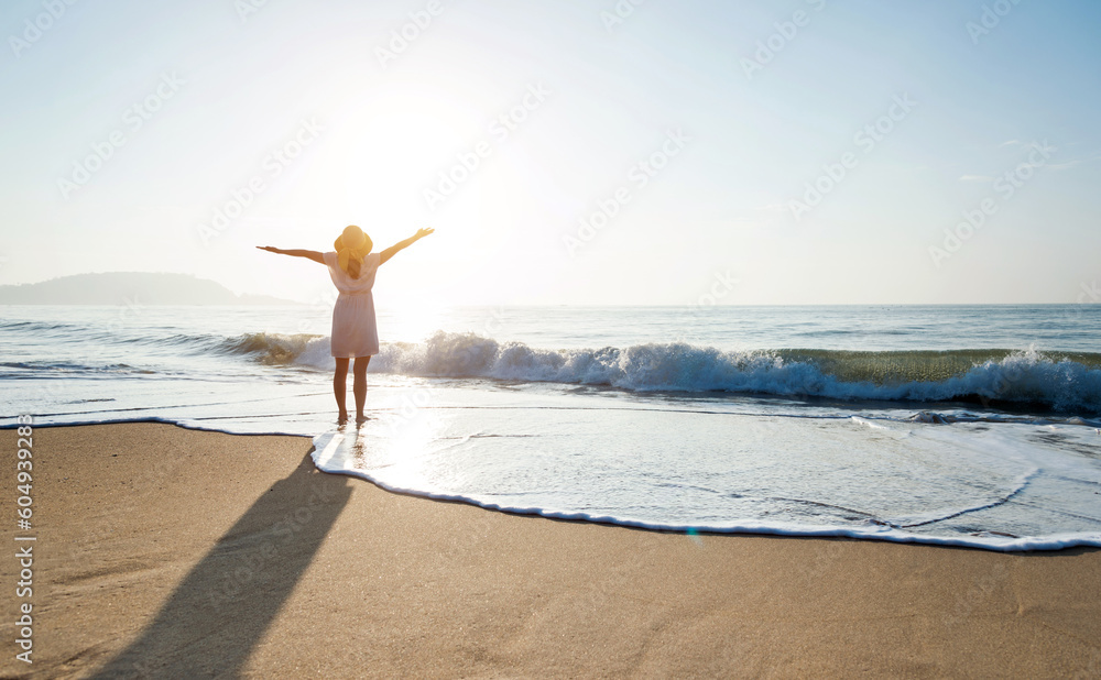 Happy woman standing on the beach with hands up. Stock Photo | Adobe Stock