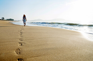 Wall Mural - Young woman walking on the beach.