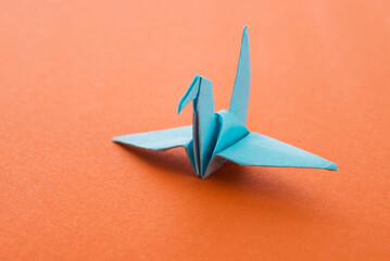 Wall Mural - Blue origami paper crane on orange background